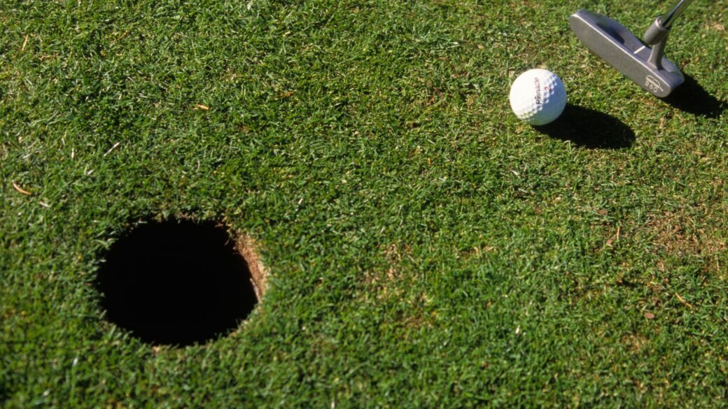 A golfer with a putter about to take a stroke
